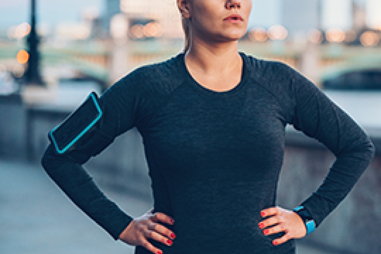 Femme dans une tenue de sport noire, les mains sur les hanches, en extérieur
