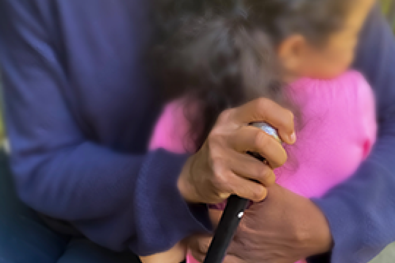 Gros plan sur une grand-mère noire tenant une canne et serrant une petite fille dans ses bras
