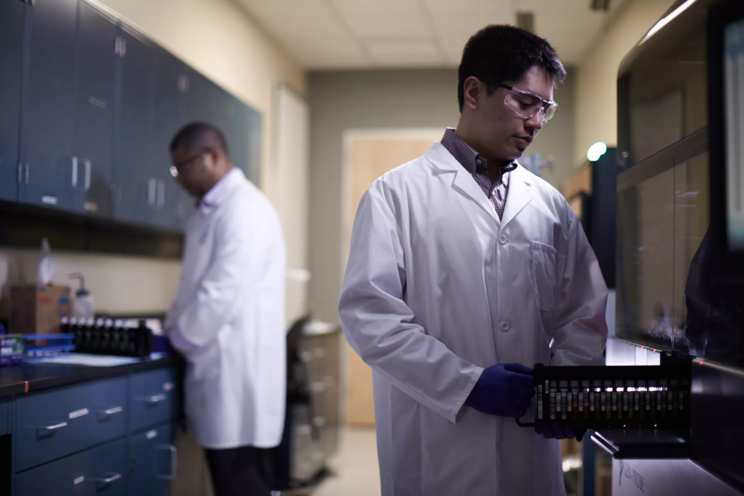 Technicien de laboratoire introduisant un plateau de flacons dans un dispositif médical