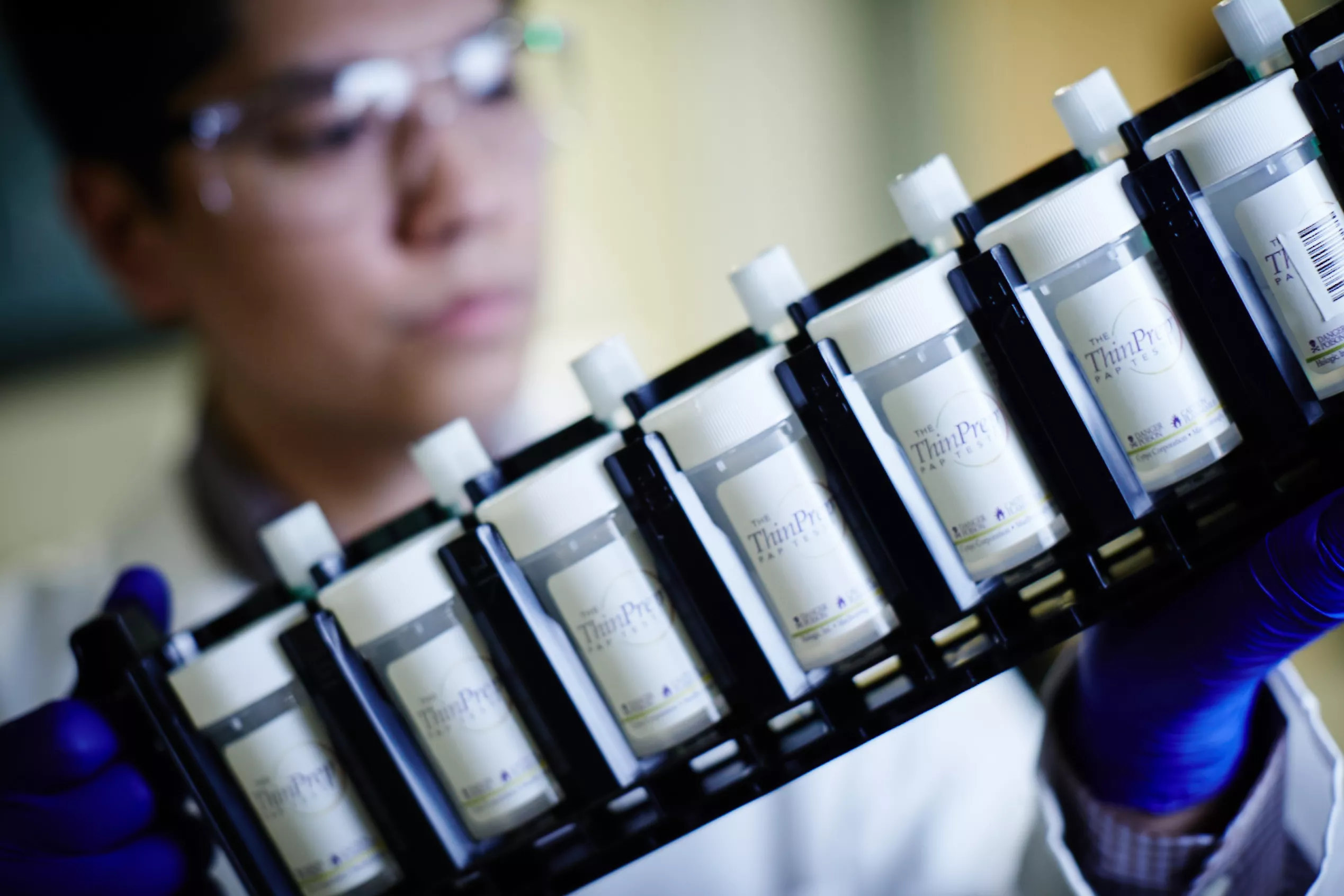 Technicien de laboratoire portant des lunettes de protection et tenant un plateau de flacons