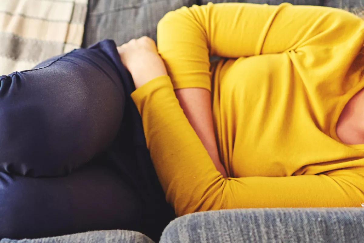 Femme allongée sur un canapé se tenant le ventre