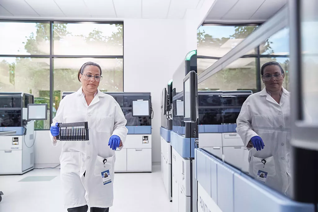 Technicienne de laboratoire transportant un plateau de flacons dans un laboratoire