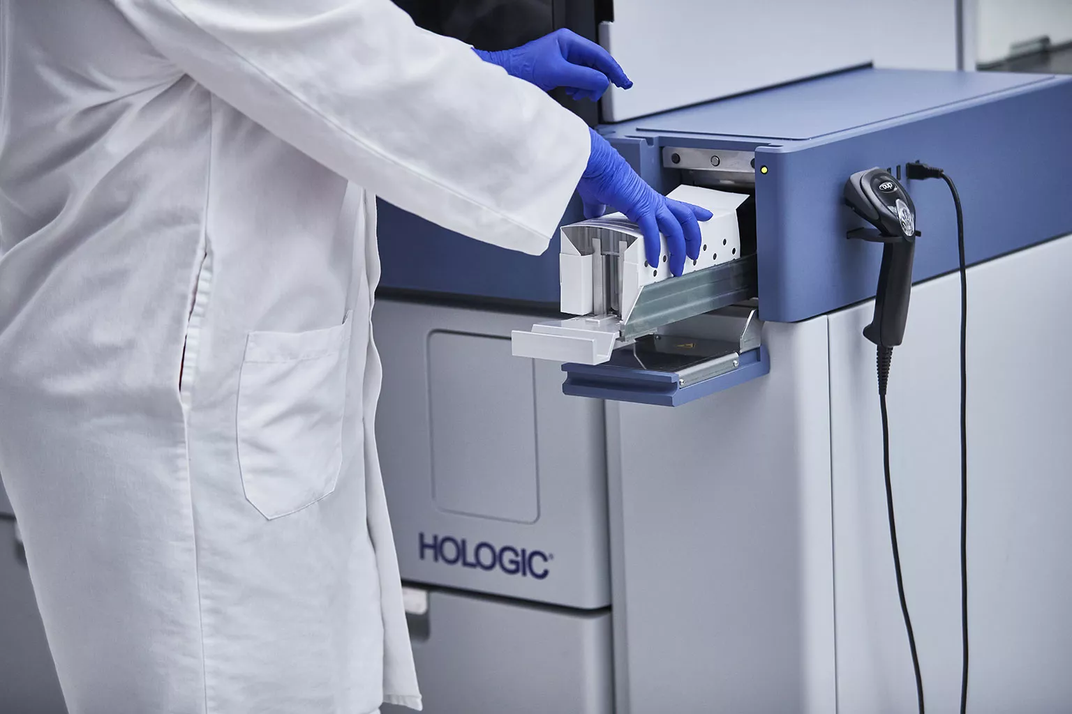 Technicien de laboratoire plaçant un plateau de tubes dans le système Panther dans un laboratoire.