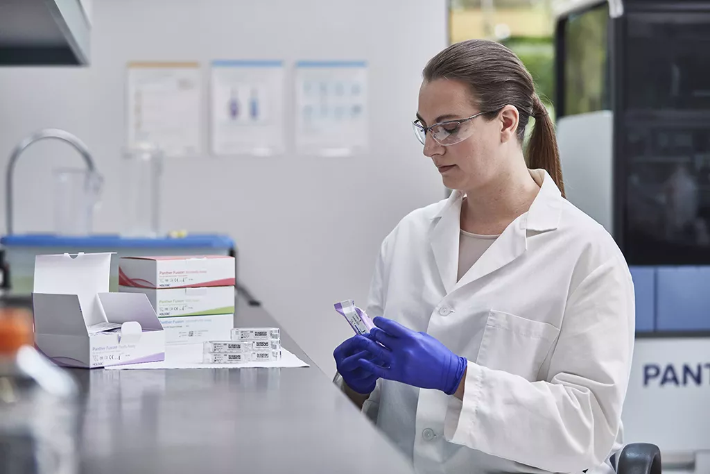 Technicienne transportant plusieurs boîtes de tests dans un laboratoire