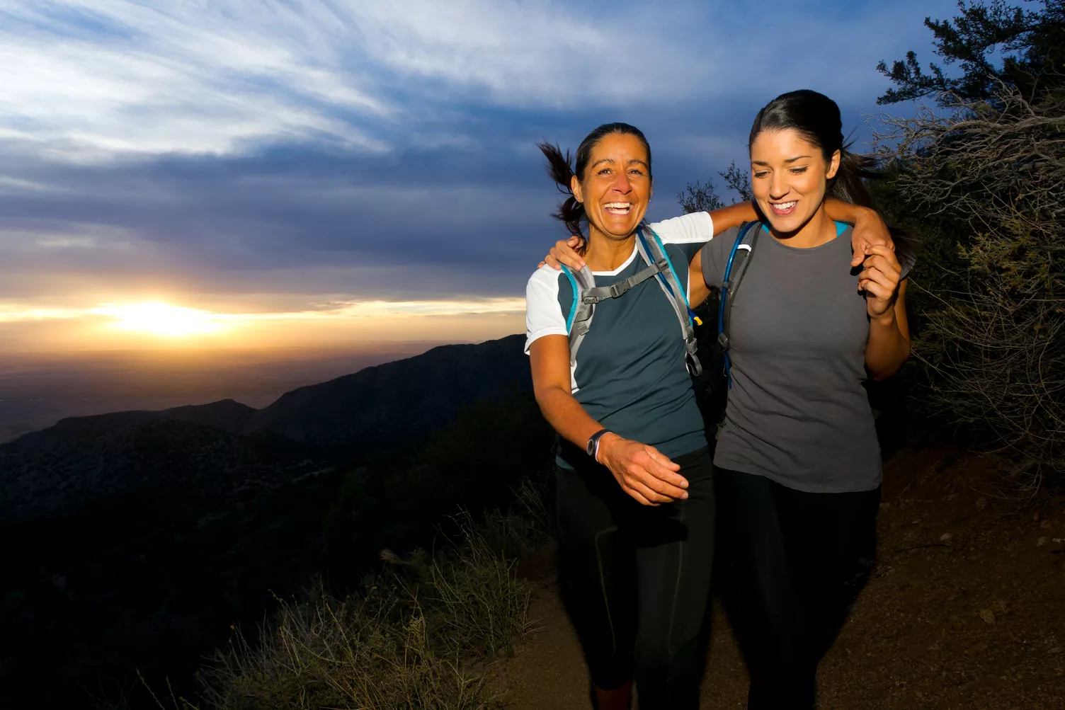 Deux femmes randonnent sur une colline au coucher du soleil