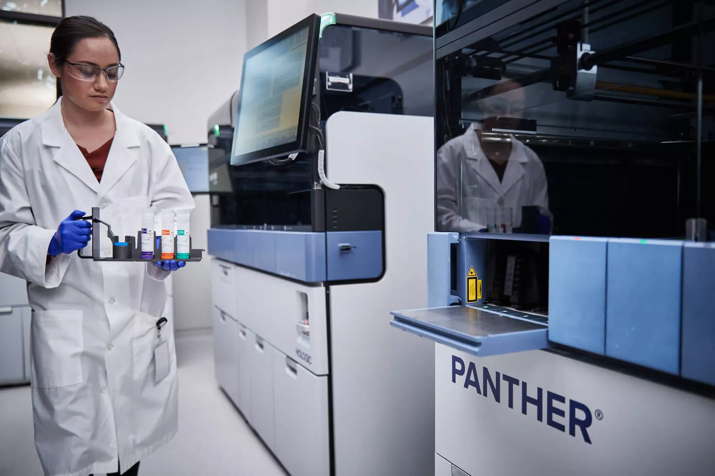 Technicienne de laboratoire transportant un plateau de flacons dans un laboratoire